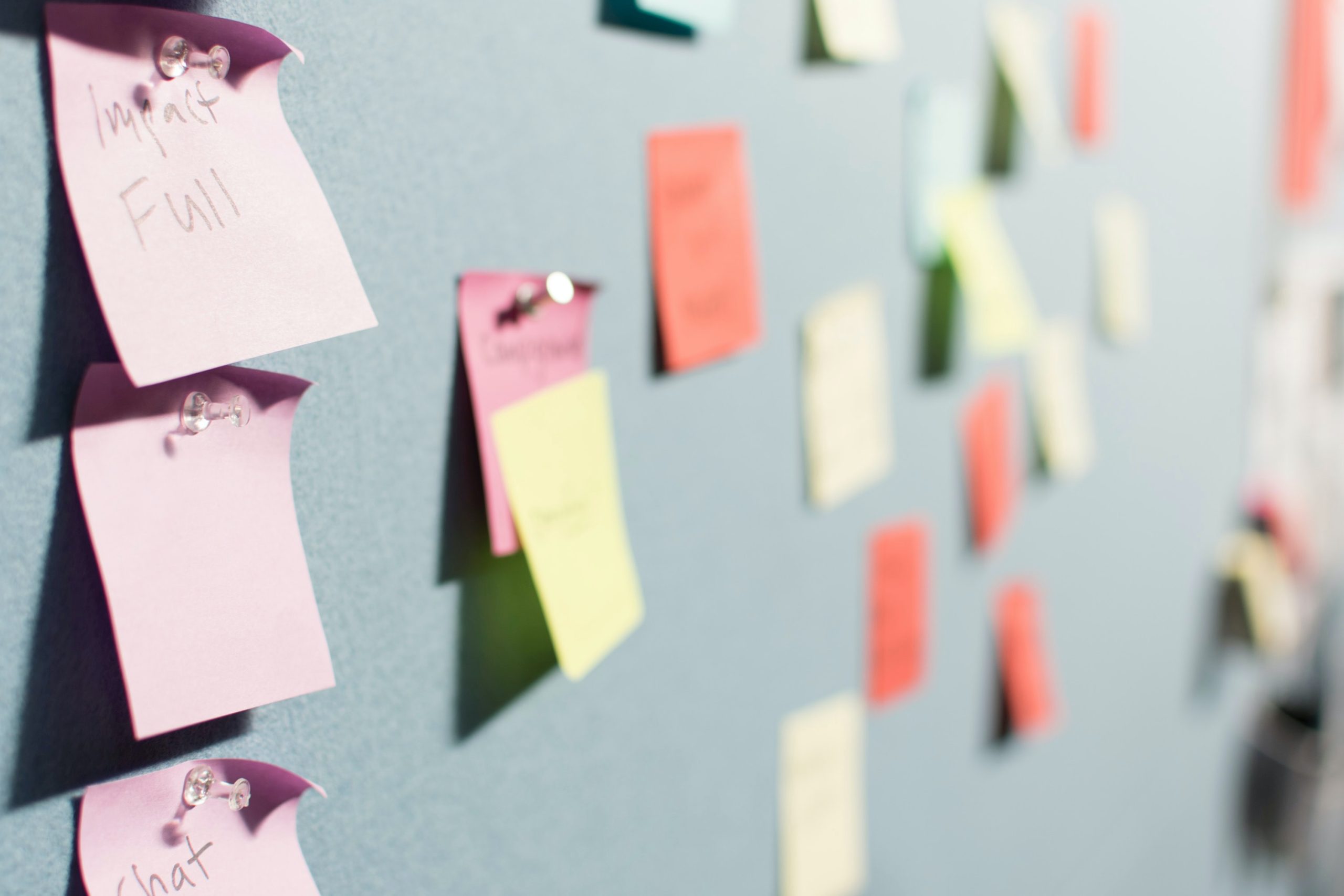 Post-it notes across a board. One in focus reads: Impact Full