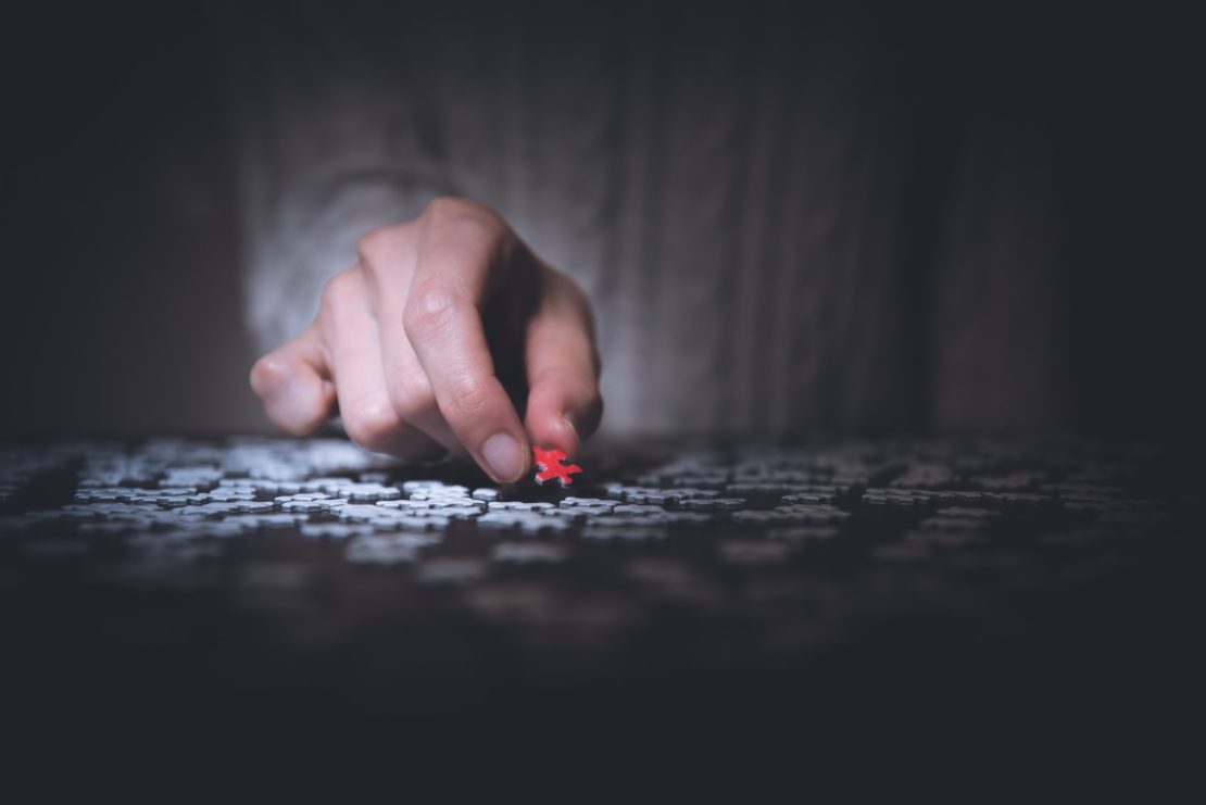 Person placing a red puzzle piece. Highlighted to symbolize significance and strategy.